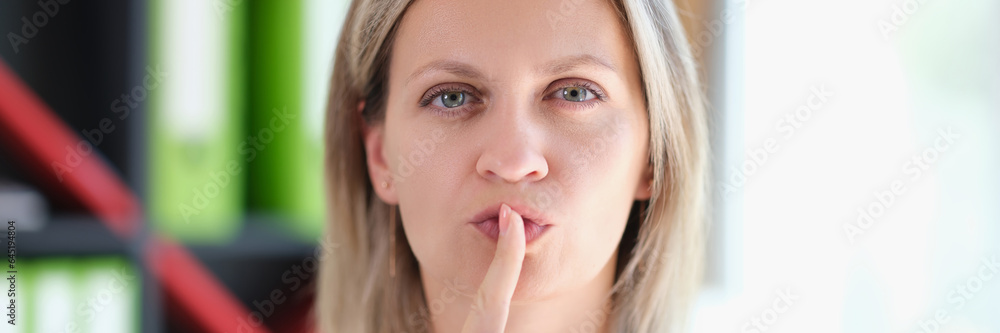 Adult woman holds finger on her lips and gestures to be silent and keep secret. Adult woman holds finger on her lips and gestures to be silent and keep secret.