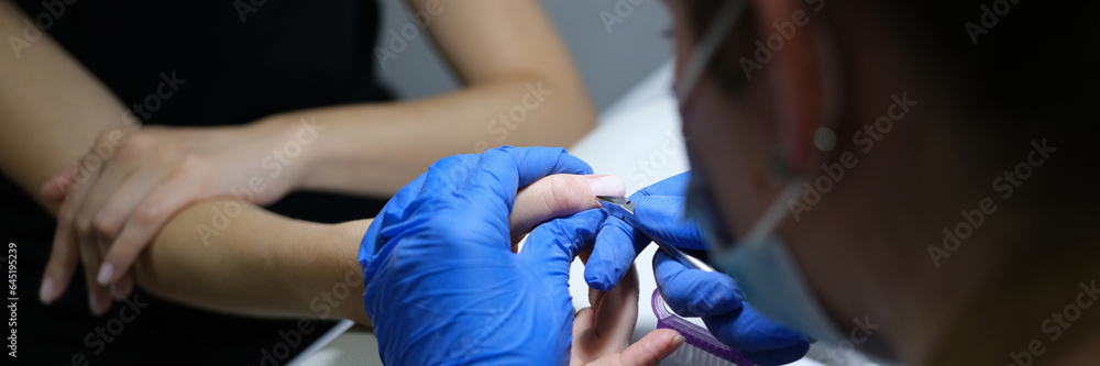 Manicurist cares client's nail cuticle in spa salon. Manicurist cares client's nail cuticle in spa salon.