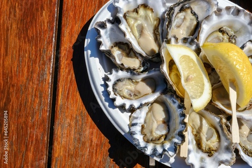 A plate of fresh Sydney rock oysters with lemon wedges on a sunny morning at Jim Wilds Oyster Shack, Greenwell Point, NSW