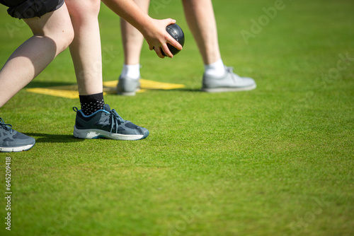 close up photo of legs of people playing bowls on a summer sunny day