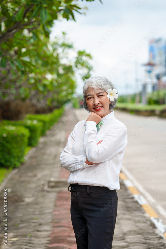 Happy mature asian woman with grey hair relaxing in park, senior serenity, refreshing break, happy mature lady enjoys relaxation at the park, breathfresh Happy mature asian woman with grey hair relaxing in park, senior serenity, refreshing break, happy mature lady enjoys relaxation at the park, breathfresh