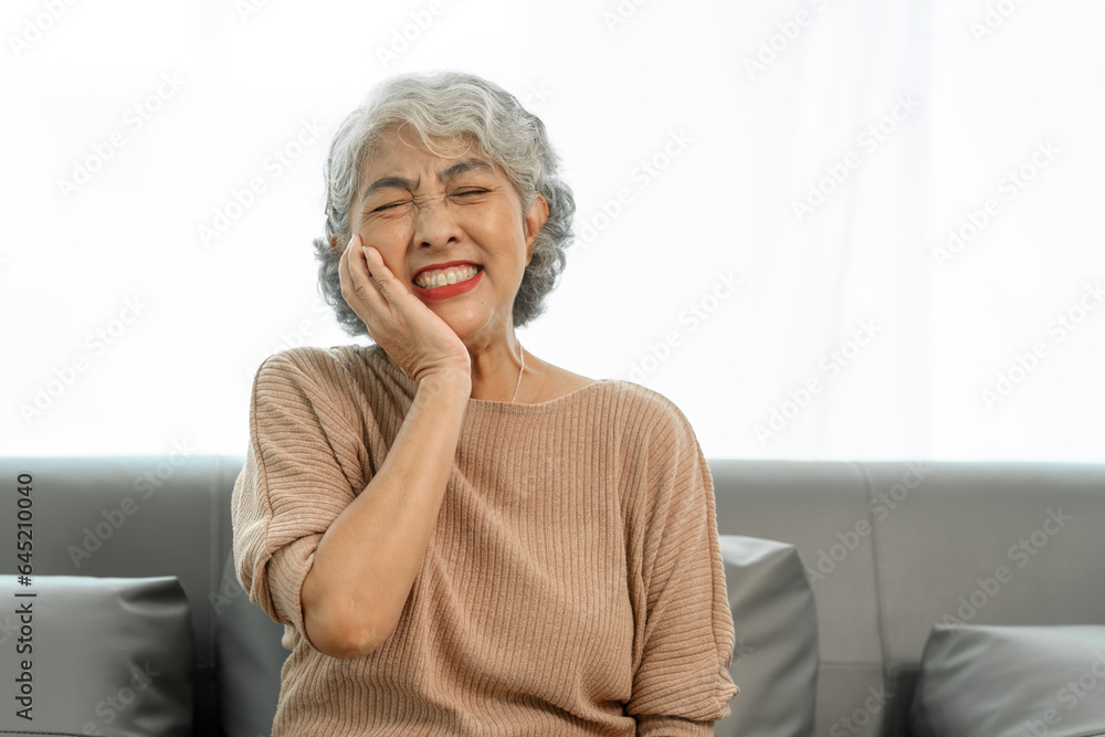 Elderly asian woman sitting on the couch, tooth decay, toothache. Elderly asian woman sitting on the couch, tooth decay, toothache.