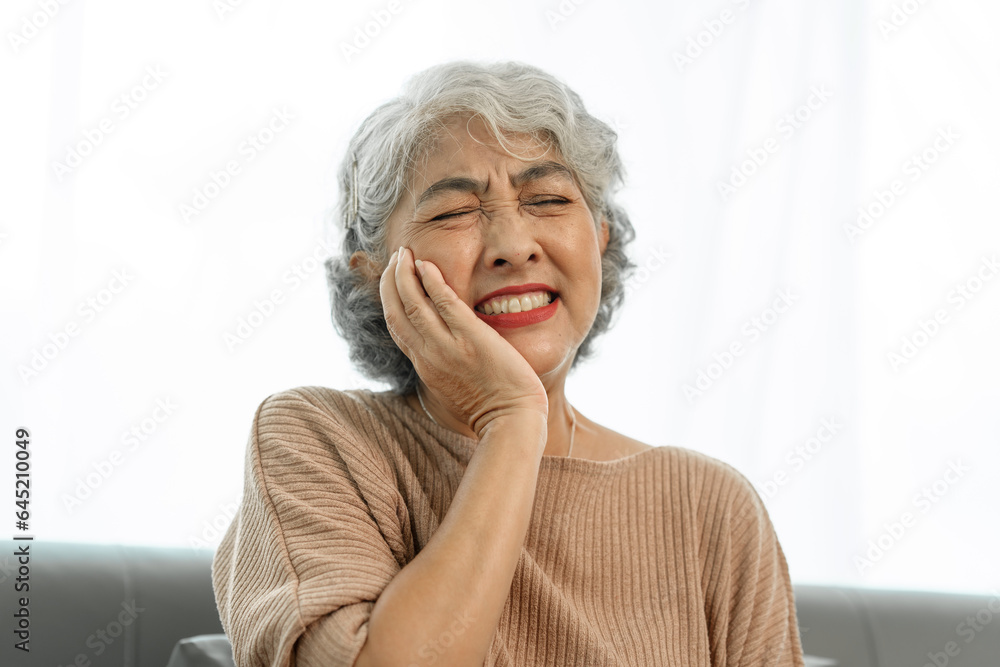 Elderly asian woman sitting on the couch, tooth decay, toothache. Elderly asian woman sitting on the couch, tooth decay, toothache.