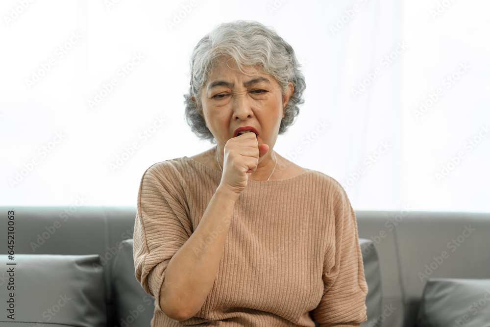 Elderly asian woman sitting on the couch, Cough, sore throat. Elderly asian woman sitting on the couch, Cough, sore throat.