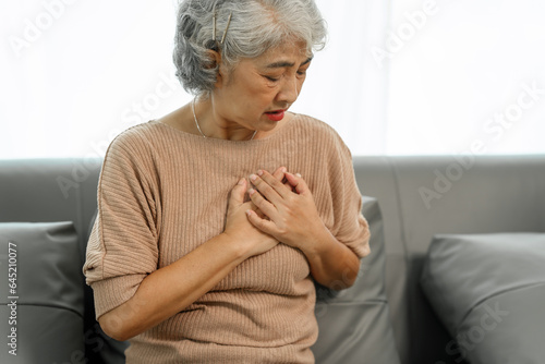 Elderly asian woman sitting on the couch, chest pain heart attact. photo