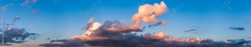Panoramic view of blue sky with fluffy sunset clouds, amazing sky background, banner. Panorama of cloudscape, atmospheric evening backdrop, wallpaper. Design style poster concept. Copy ad text space