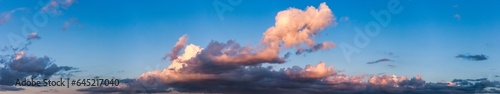 Panoramic view of blue sky with fluffy sunset clouds, amazing sky background, banner. Panorama of cloudscape, atmospheric evening backdrop, wallpaper. Design style poster concept. Copy ad text space