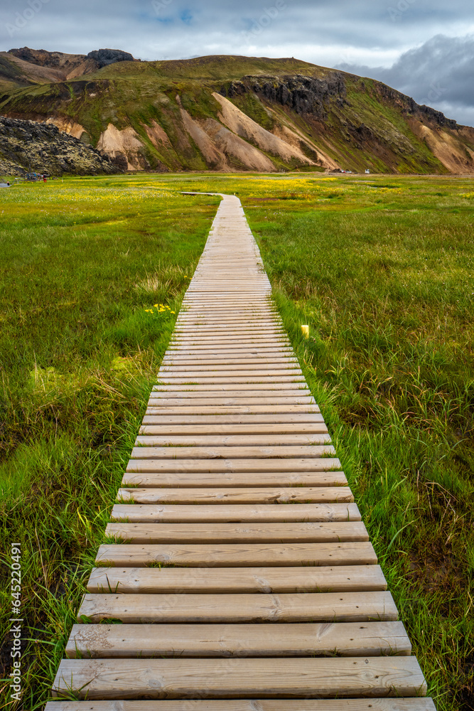 Landmannalaugar, Iceland. Camping site and mountain hut with a wooden path to bathing pool and beautiful Icelandic landscape of colorful rainbow volcanic Landmannalaugar mountains, 