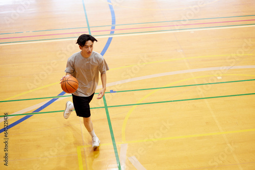 体育館でバスケットボールの練習をする日本人大学生の男性 photo
