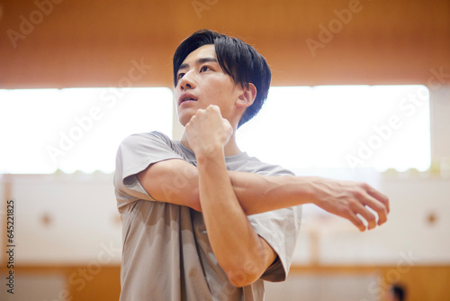 体育館でストレッチを行う日本人大学生の男性 photo
