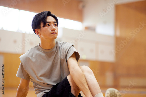 体育館でストレッチを行う日本人大学生の男性 photo