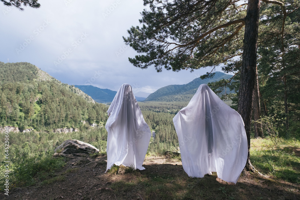 Couple of ghosts in daytime with mountain valley view
