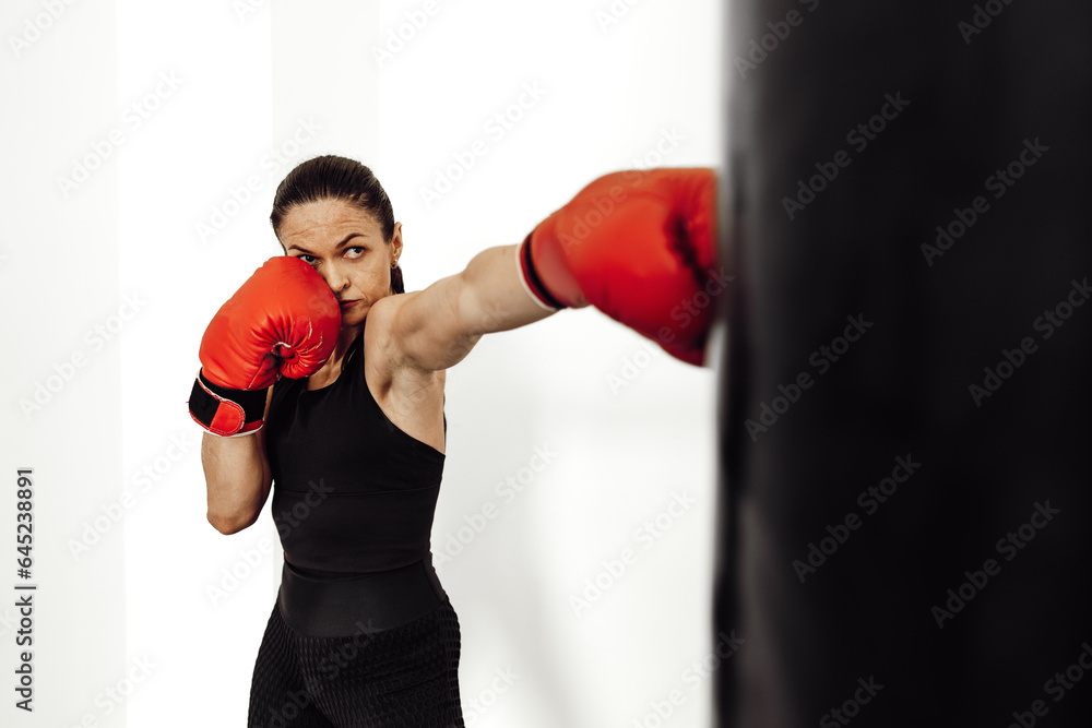 Woman athlete in red boxing gloves hits a pear in a gym Woman athlete in red boxing gloves hits a pear in a gym