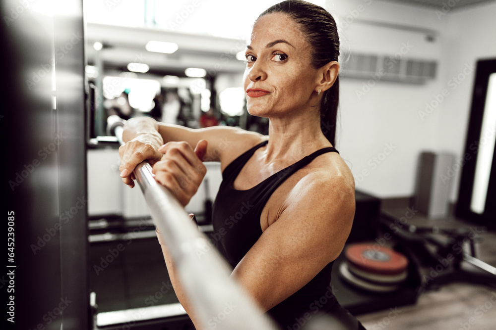 Fit woman doing squats with barbell in a gym Fit woman doing squats with barbell in a gym