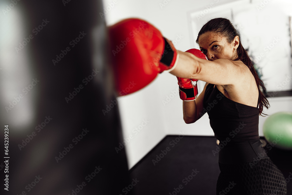 Woman athlete in red boxing gloves hits a pear in a gym Woman athlete in red boxing gloves hits a pear in a gym
