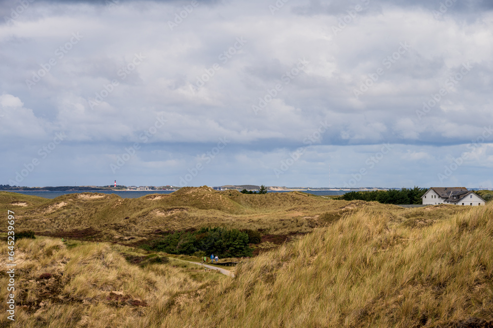 Dramatische Wolken im Dünenbereich der Nordseeinsel Amrum der Blick geht hinüber zur Nachbarinsel Sylt mit dem Leuchtturm von Hörnum Dramatische Wolken im Dünenbereich der Nordseeinsel Amrum der Blick geht hinüber zur Nachbarinsel Sylt mit dem Leuchtturm von Hörnum