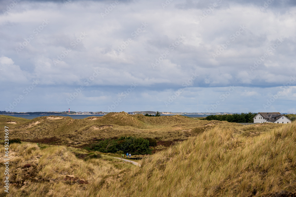 Dramatische Wolken im Dünenbereich der Nordseeinsel Amrum der Blick geht hinüber zur Nachbarinsel Sylt mit dem Leuchtturm von Hörnum