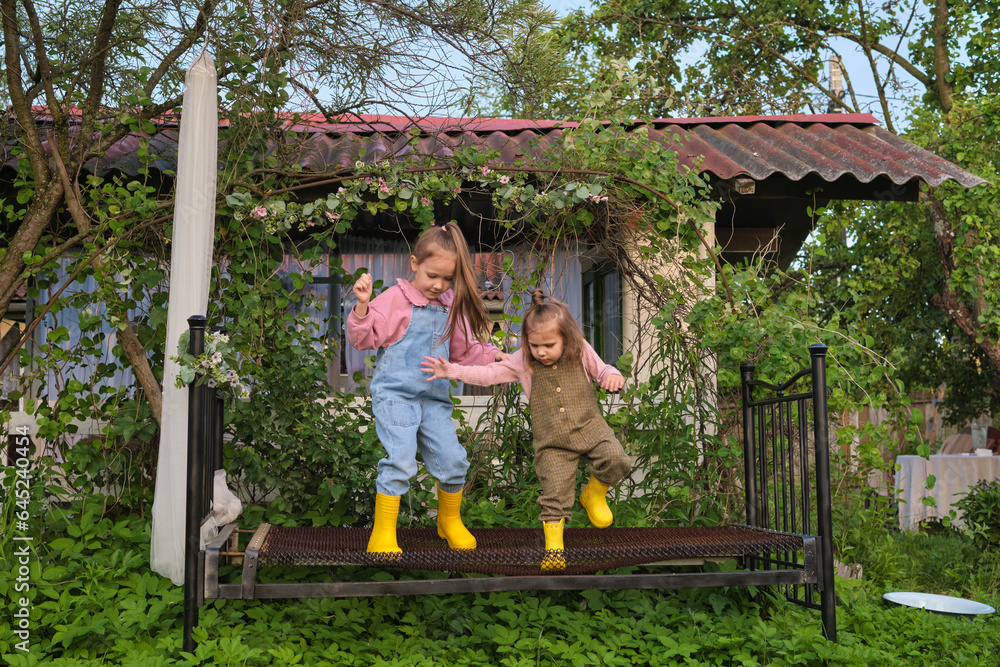 Obraz premium Hidden behind a house, an overgrown garden becomes the stage for countless stories and adventures, as these girls demonstrate. Magic Hidden in Our Backyards.
