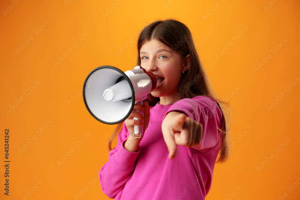 Teen girl making announcement with megaphone on yellow background Teen girl making announcement with megaphone on yellow background
