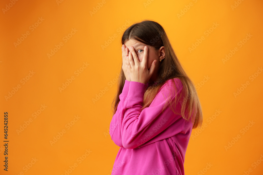 Anxious teen girl looking scared or worried on yellow background Anxious teen girl looking scared or worried on yellow background