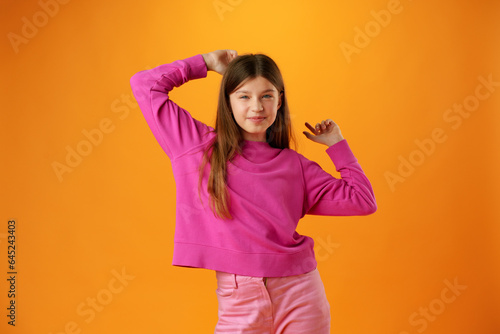Portrait of a joyful happy teenage girl celebrating success on yellow background