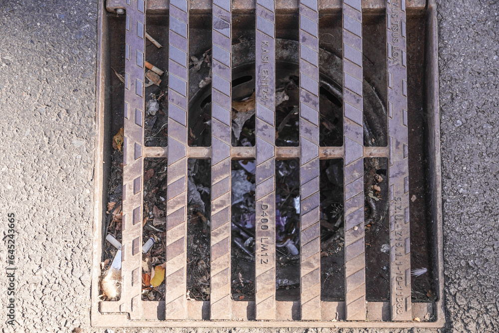 drainage grate for rainwater on the street clogged with small debris. High quality photo drainage grate for rainwater on the street clogged with small debris. High quality photo