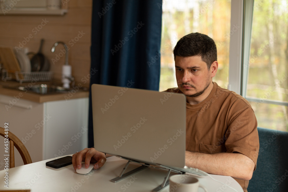 Fototapeta premium A man works on a laptop from home, runs a small business