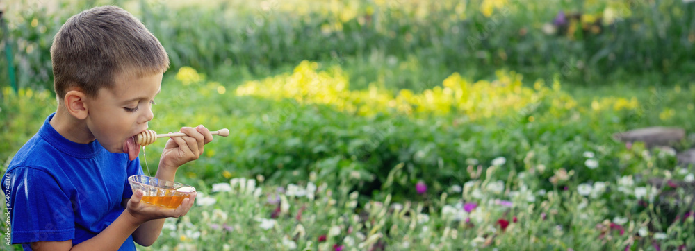 boy eats honey in nature, homemade honey. Selective focus boy eats honey in nature, homemade honey. Selective focus