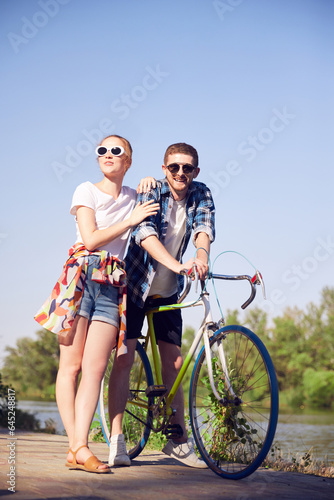 Attractive woman with her boyfriend enjoying riding a bicycle outdoor wearing summer clothes. Adventure and vacations concept.
