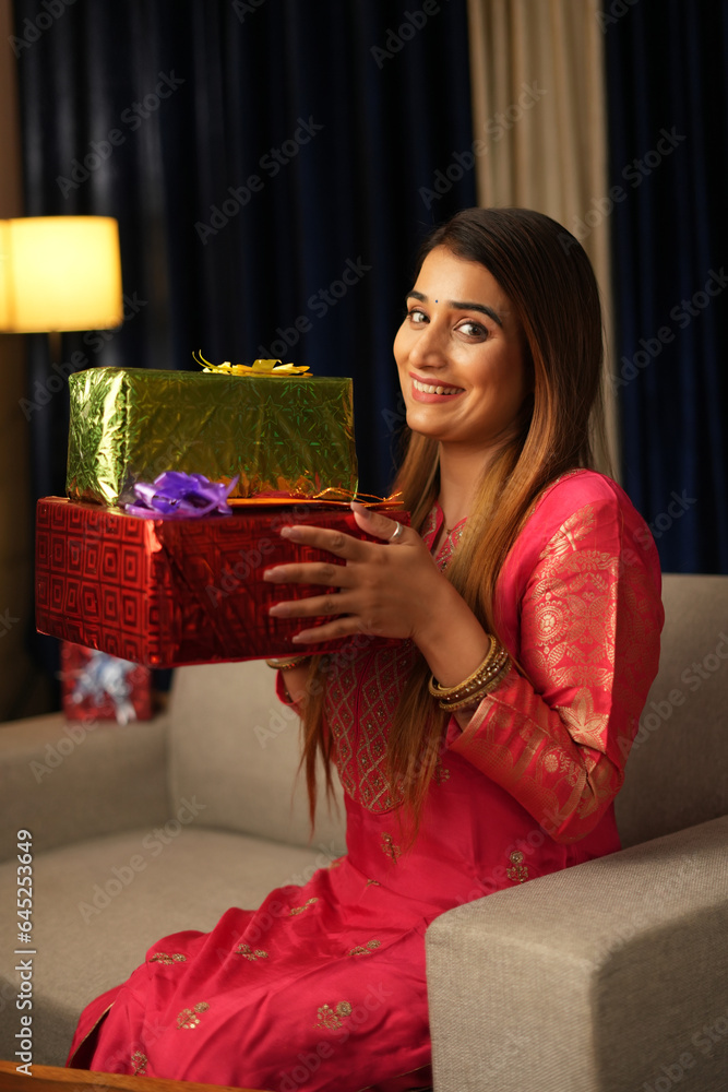 woman sitting on sofa holding gift boxes woman sitting on sofa holding gift boxes