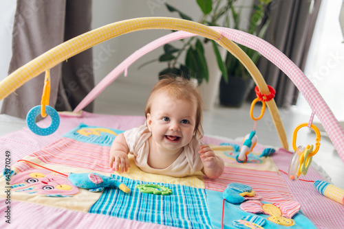 Cute satisfied child lying on a bright children's educational mat