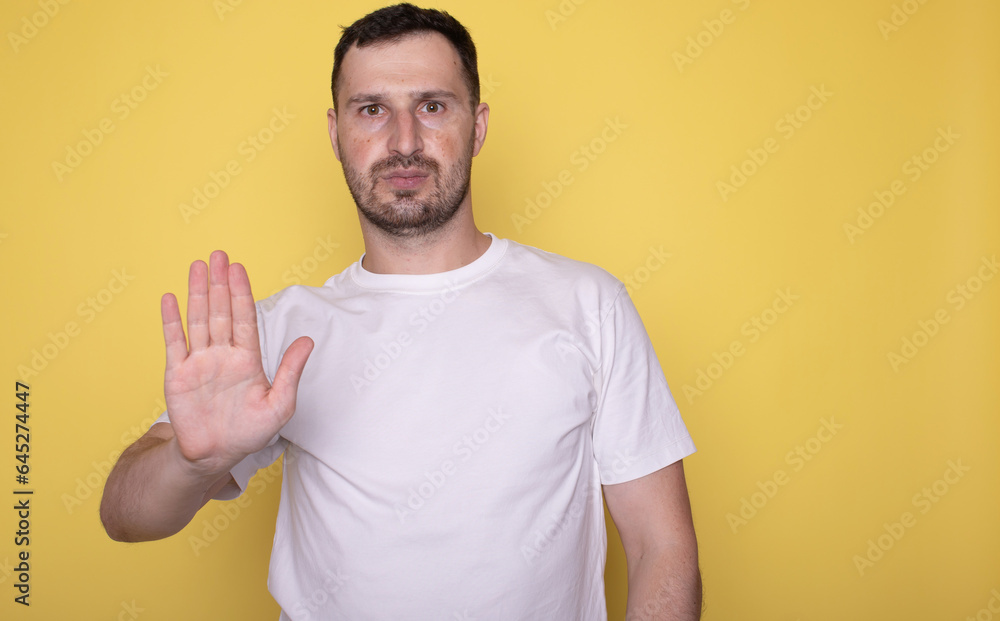 Man over isolated yellow background making stop gesture with hand. Man over isolated yellow background making stop gesture with hand.
