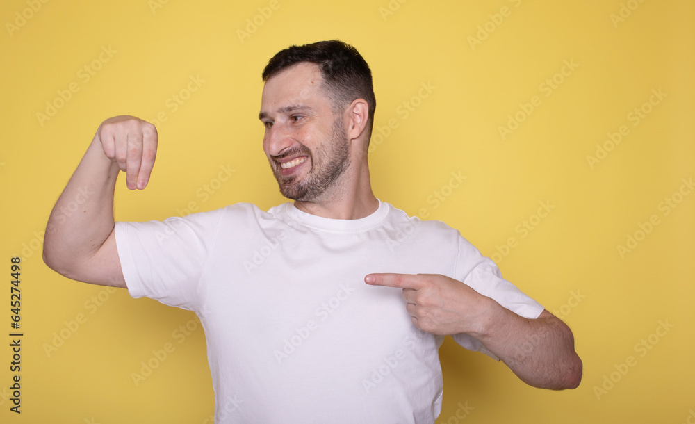 Handsome young man point by finger right side with happy face looking at camera on yellow isolated background. Handsome young man point by finger right side with happy face looking at camera on yellow isolated background.