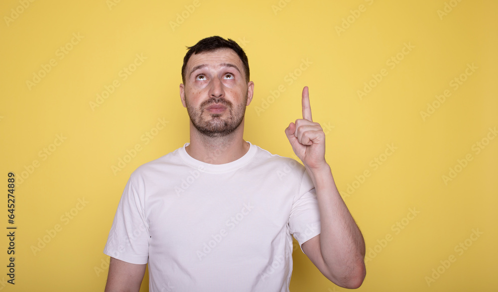 Portrait of a happy bearded man pointing fingers up at copy space isolated over yellow background. Portrait of a happy bearded man pointing fingers up at copy space isolated over yellow background.