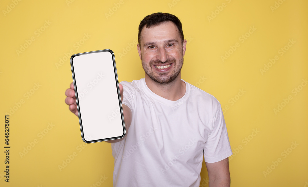 Happy excited young man showing smartphone isolated on yellow background presenting cellphone mobile offer application ads concept. Happy excited young man showing smartphone isolated on yellow background presenting cellphone mobile offer application ads concept.