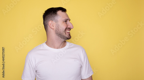 Side view profile of cheerful young smiling unshaved caucasian handsome man isolated on yellow background.