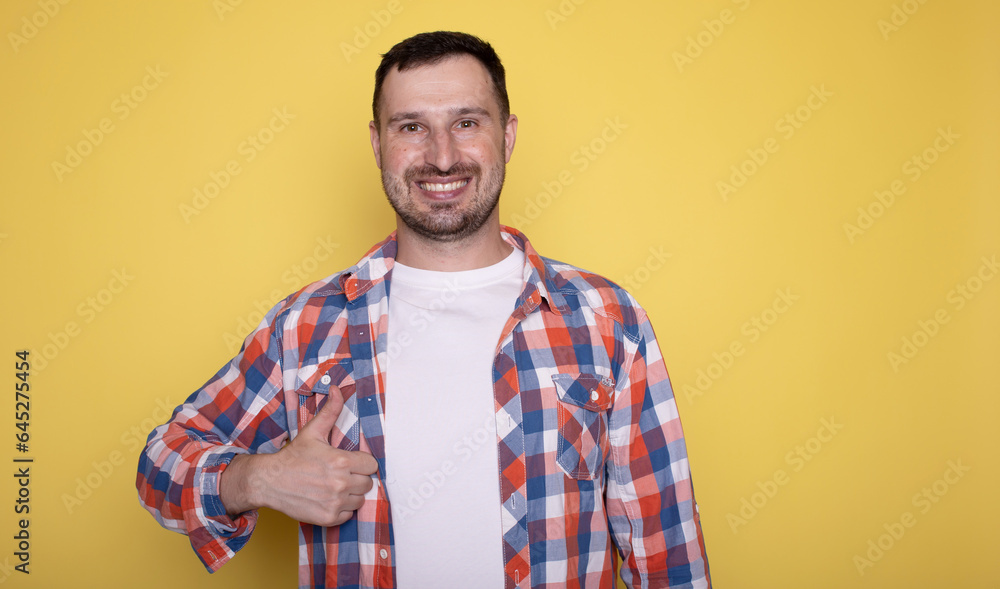 Portrait of cheerful man smiling and showing thumbs up at camera isolated over yellow background. Portrait of cheerful man smiling and showing thumbs up at camera isolated over yellow background.
