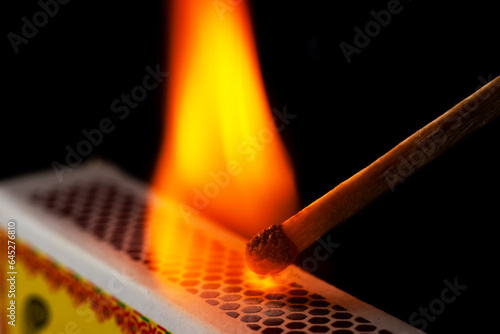 Fotografija A matchstick lights after it is struck agains the flint surface of a match box