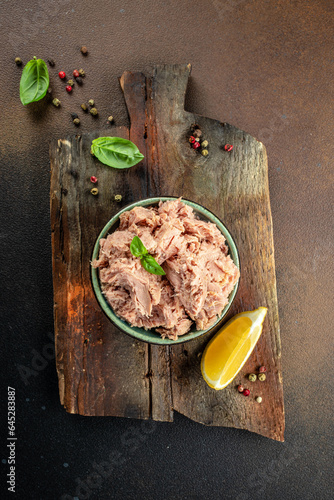 Bowl with canned Tuna on a wooden board. Food recipe background. Close up