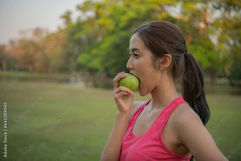 Woman in sportswear eating healthy fruit. She is eating green apples to lose weight.