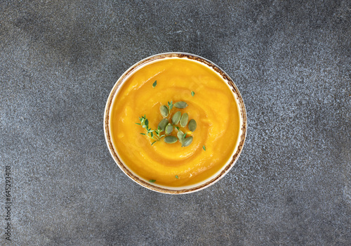 Pumpkin or carrot soup with a silky texture of pumpkin seeds on a white background. Top view.