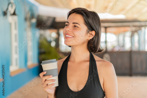 Young pretty Bulgarian woman at outdoors holding a take away coffee with happy expression