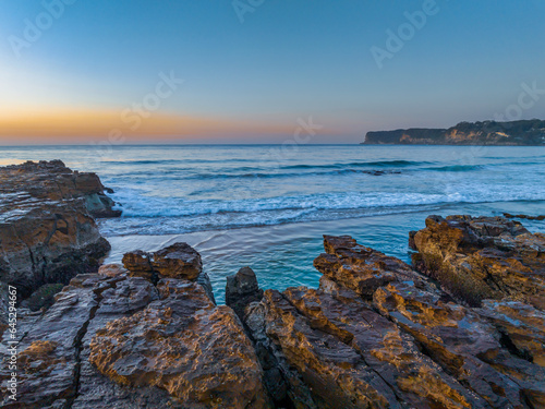 Sunrise over the ocean and rock platform with clear skies