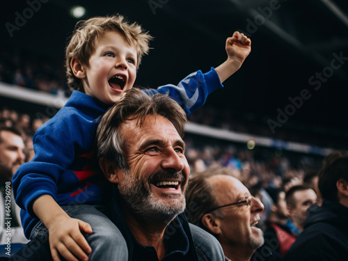 French father and son in stands, filled with enthusiastic supporters of rugby or football team wearing blue clothes to support national sports team
