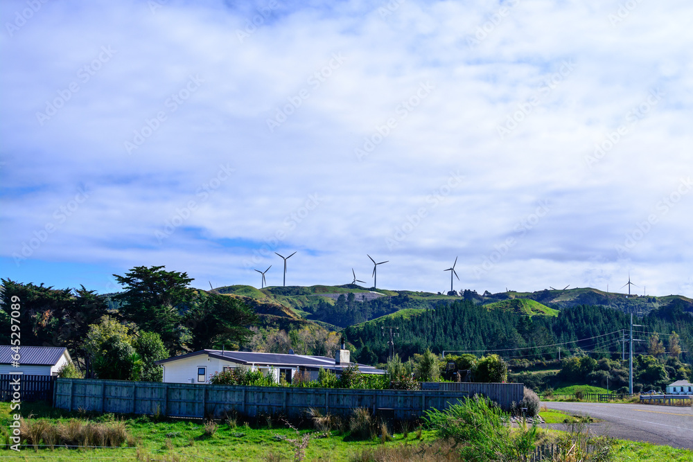 Iconic landscape with wind farm on the top of a mountain range under blue sky with white clouds. Concept of alternative energy and sustainability. Palmerston North, New Zealand Iconic landscape with wind farm on the top of a mountain range under blue sky with white clouds. Concept of alternative energy and sustainability. Palmerston North, New Zealand