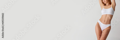 Banner. Cropped image of slim female body, stomach in white underwear isolated over light studio background. Well-being.