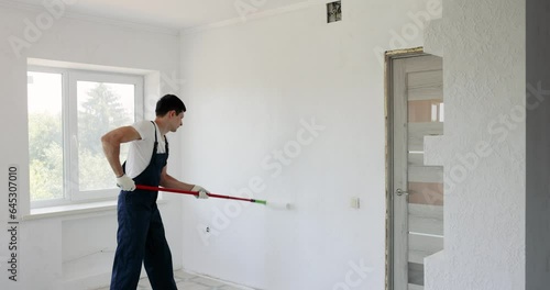 man painting wall in white color with roller