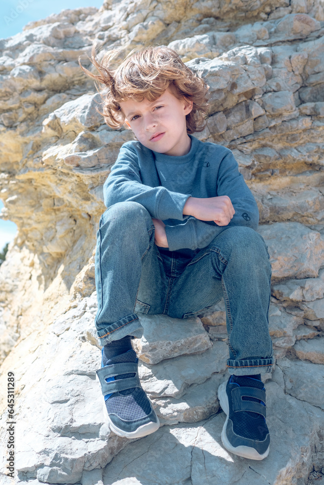 Calm boy sitting on cliff Calm boy sitting on cliff