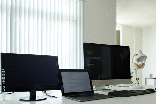 Laptop and computers with programming code on table in office
