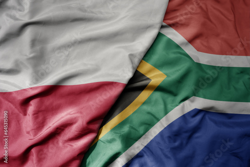 big waving national colorful flag of poland and national flag of south africa .